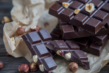 A piece of chocolate with hazelnuts and nuts on a table