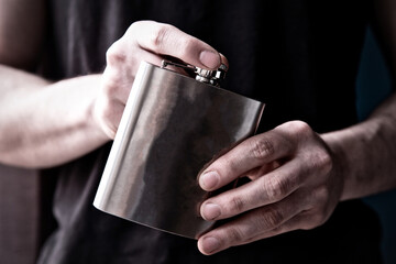 Young man holding a stainless steele Hip Flask with liquor, alcohol and booze concept