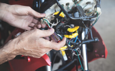 Obraz premium Mechanic man wiring the electrical cables motorcycle.