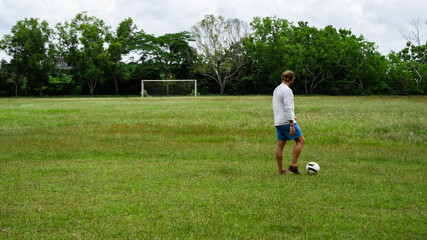 young attractive man training with soccer ball on soccer green field background