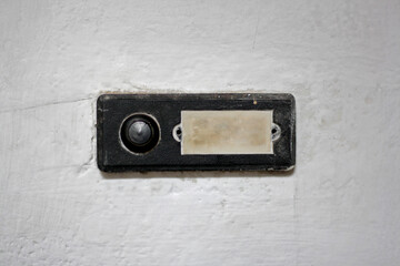 A doorbell on a white wall, close up