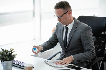 Handsome businessman disinfecting desk in the office.	
