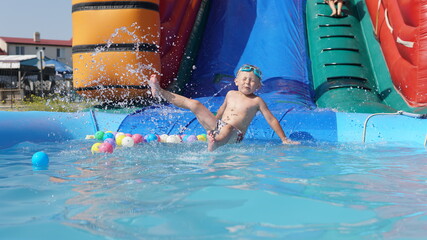 Child jump on inflatable water slide. Aqua amusement park of sea resort.
