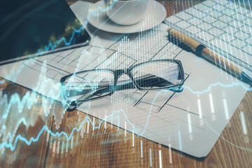 Financial chart hologram with glasses on the table background. Concept of business. Double exposure.