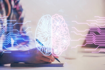 Double exposure of woman's writing hand on background with brain hud. Concept of learning.