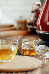 Glass jar of honey on kitchen table, close up