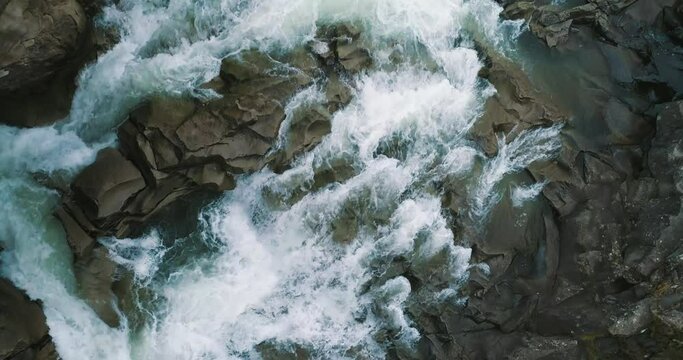 Aerial Vertical View Over The Surface Of A Mountain River Prut, Yaremche, Ukraine. Drone view of waterfall. Turquoise water flows over the stones.