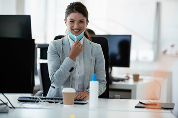 Beautiful businesswoman with medical mask working in office. Young businesswoman working on lap top.	