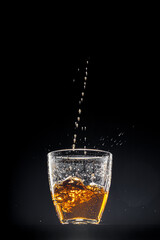 Whisky pouring into a glass on black background