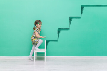 The child climbs onto a hand-drawn ladder. The beginning of a career concept.Funny little girl on a turquoise background with a place for text.