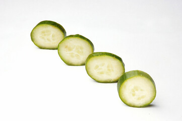 Pieces of cucumber in a row on white background .