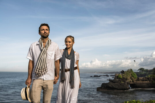 Asia, Indonesia, Bali, young Caucasian couple, wearing smart casual clothing, enjoying a visit to the famous Hindu temple Tanalot, which is one of the Mother temples, situated on the seashore.