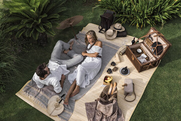 Asia, Indonesia, Bali, young Caucasian couple enjoying a luxury, authentic picnic, set in a tropical garden, , wearing smart casual clothing, while on holiday.