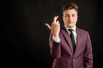 Law student with blond hair dressed in burgundy jacket, white shirt and black tie showing good luck