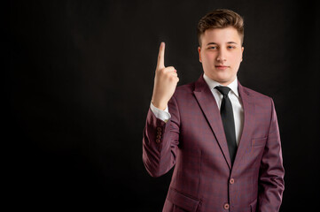 Law student with blond hair dressed in burgundy jacket, white shirt and black tie counting one with his finger