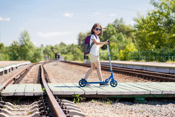 Crossing the railway tracks made of wood across the railway tracks  in the daytime. Schoolgirl ...