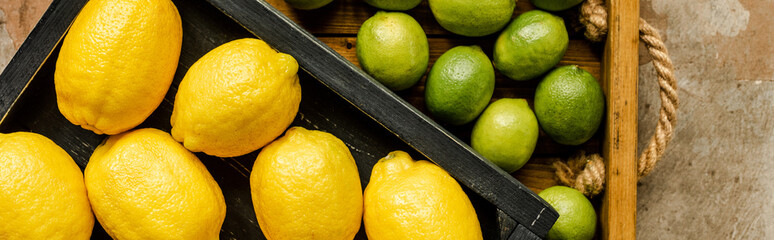 top view of lemons and limes in wooden boxes on weathered surface, panoramic shot