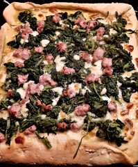 closeup of homemade white pizza with mozzarella, sausage and Neapolitan vegetables called "friarielli" 
before cooking in a wood oven
