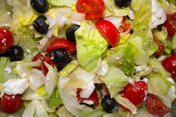 closeup of salad, tomatoes, onions and black olives washed and cut with the addition of Greek 
sheep and goat cheese with semi-hard paste left to mature in brine called 