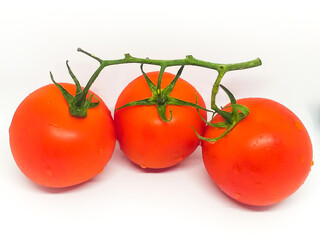 Three ripe juicy tomatoes on a branch. Isolate on a white background: red tomatoes with drops of water. Healthy fresh vegetables, healthy foods, a source of vitamins and fiber.