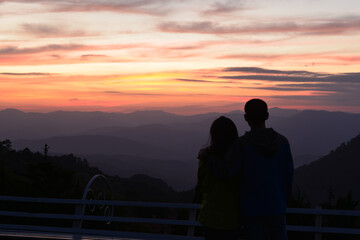 Fototapeta na wymiar silhouette of a man with his lover is waiting for Amazing twilight over the mountain at Doi Inthanond national park. Chiang Mai, Thailand.