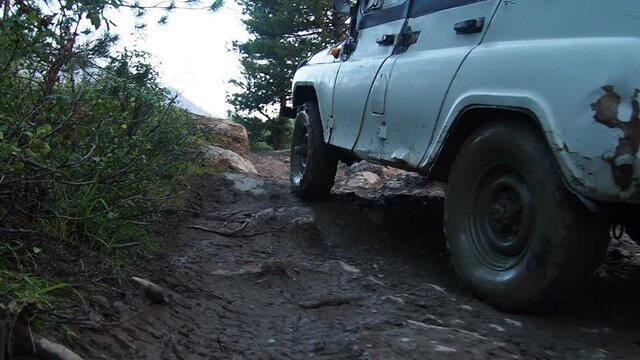 a powerful passable car rides over rocks in a mountain valley. Slow motion