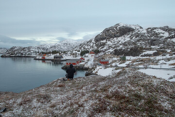 A hiker takes a photograph of a arctic village. 