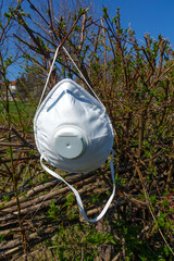 White used anti-virus filter mask hanging on branches. Corona virus spring time