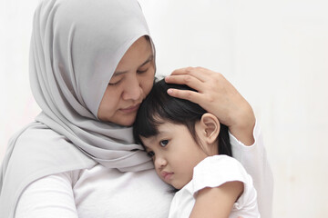 Asian muslim mother hijab calming her sad and crying daughter, single mom and baby girl together