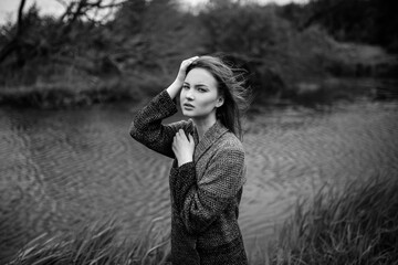 Girl model portrait near the river with hair. Pensive look. Beautiful eyes. Stylish clothes on the nature. Trees and plants.