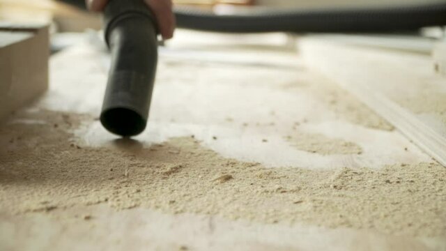 Close up male hand vacuuming sawdust on a work bench, day time static shot