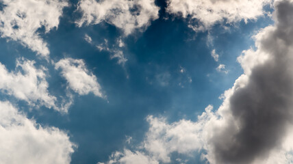 Background of bright blue sky and floating white clouds. Dramatic sky, weather before rain with...
