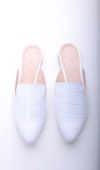 Fototapeta premium beautiful women's shoes on legs and layouts, leather white mules and loafers, in the interior of a room or office, a girl shoes, blue skirt and white shoes, a noble and elegant style, modern and trend