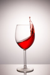 A splash of red wine in a glass on a white background