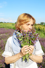 Happy woman holding fresh flowers at the field in the countryside. 