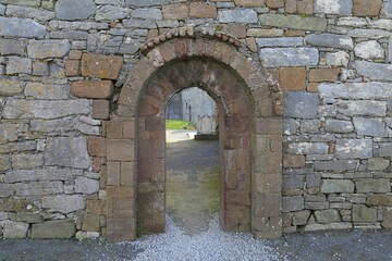  A small arched doorway leading into a ruined building.