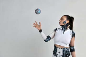 beautiful brunette girl in a robot suit holds a model of our planet in her hands and studies it
