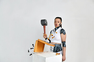 beautiful brunette girl in a robot suit beats with a hammer on a chessboard
