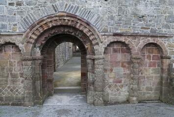 A decoratively carved archway over a door leading into the transept of a ruined church.
