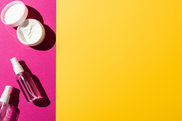top view of spray bottles with antiseptic near hand cream on pink and yellow