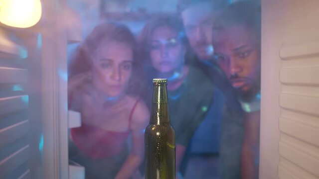 Sad diverse friends look at last beer bottle in fridge