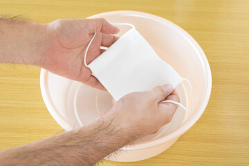 布マスクを水で手洗いする男性の手元