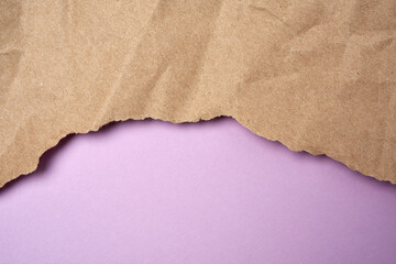 crumpled sheet of brown wrapping paper with torn edges on a purple background