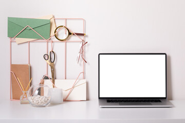 Fototapeta na wymiar Laptop with blank white screen on office desk interior. Stylish gold workplace mockup table view.