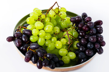 red and green grapes on a plate isolated on a white background