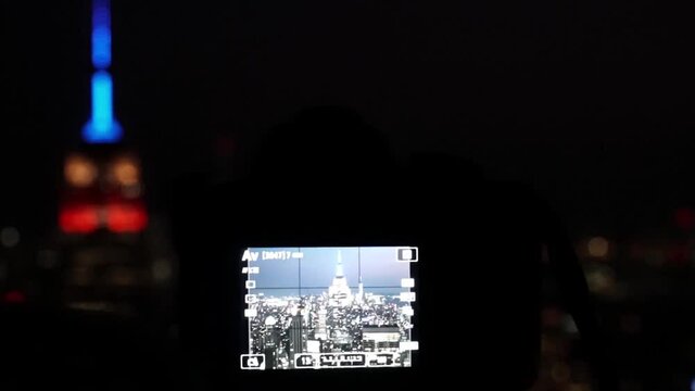 Taking a long exposure picture at night of Empire State Building with DSLR camera. Blurred Empire State Building lights in the background.