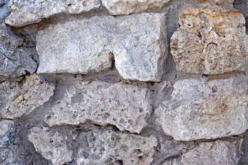 Masonry stone wall. Ancient medieval stone masonry. Texture of a fragment of a wall of an old structure. A background for design and creative work.
