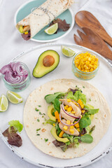 Fresh tortilla wraps with chicken, mushrooms and fresh vegetables on wooden board