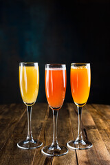 Three different sparkling fruity cocktails, red, yellow and orange, in flute glasses