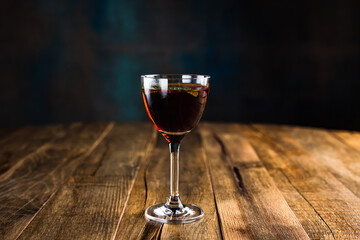 A classic sour cocktail in a nick and nora glass garnished with a mint leaf on wooden table